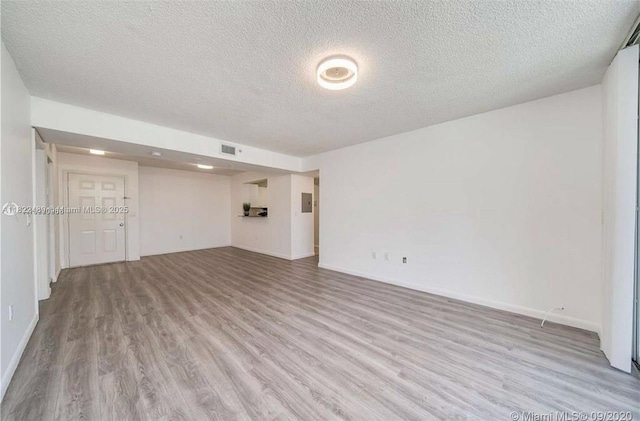 2711 Ocean Club Blvd Unit 207, Hollywood, FL 33019 - unfurnished living room with a textured ceiling, light wood finished floors, and electric panel