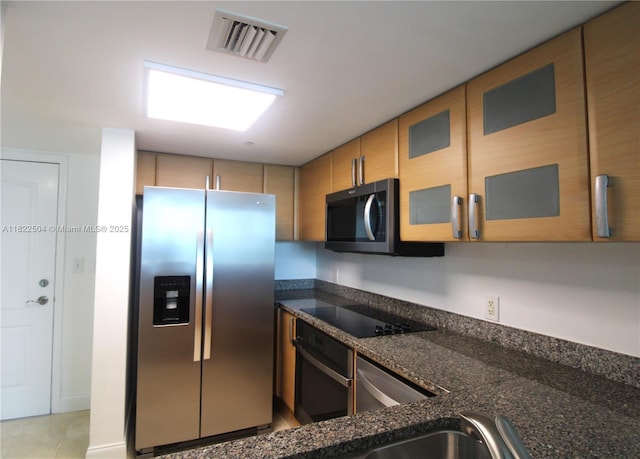 2101 Brickell Ave Unit 1711, Miami, FL 33129 - kitchen featuring black appliances, glass insert cabinets, dark stone counters, and brown cabinetry
