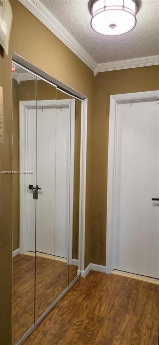 9750 NW 14th St Unit 30-5, Coral Springs, FL 33071 - unfurnished bedroom with wood finished floors, a textured ceiling, a closet, and ornamental molding
