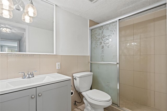 301 NW 177th St Unit 104, Miami Gardens, FL 33169 - bathroom featuring a stall shower, vanity, tile walls, and a textured ceiling