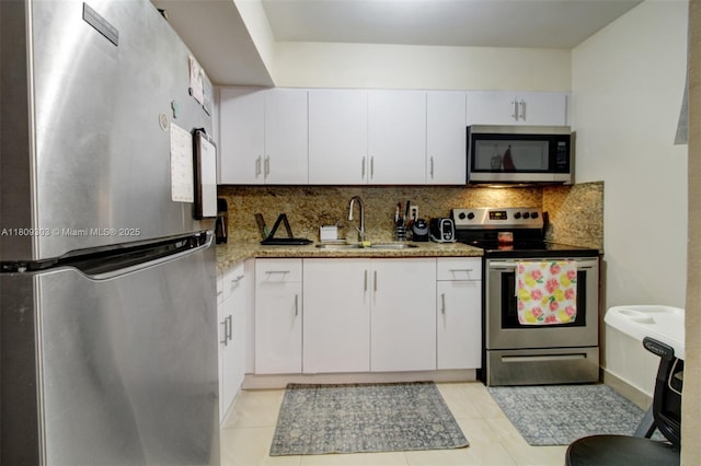 8095 NW 8th St Unit 209, Miami, FL 33126 - kitchen featuring appliances with stainless steel finishes, decorative backsplash, white cabinetry, light tile patterned floors, and light stone countertops
