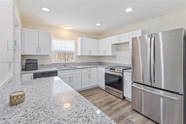 1712 Melvin Ave, Orlando, FL 32806 - kitchen featuring stainless steel appliances, white cabinets, light stone counters, light wood-type flooring, and recessed lighting