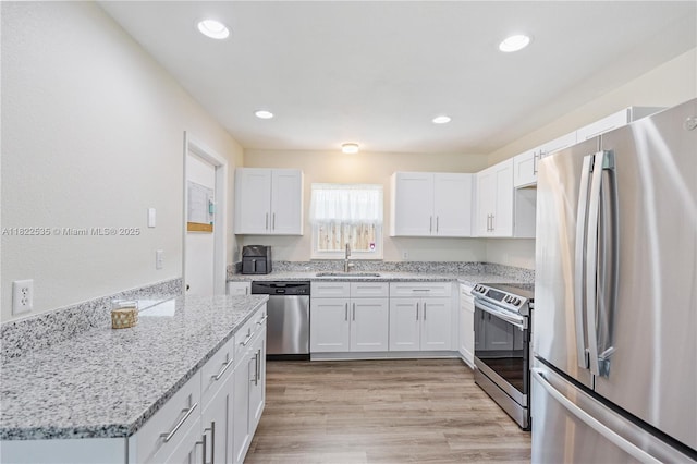 1712 Melvin Ave, Orlando, FL 32806 - kitchen with stainless steel appliances, white cabinetry, light stone countertops, light wood-style floors, and recessed lighting