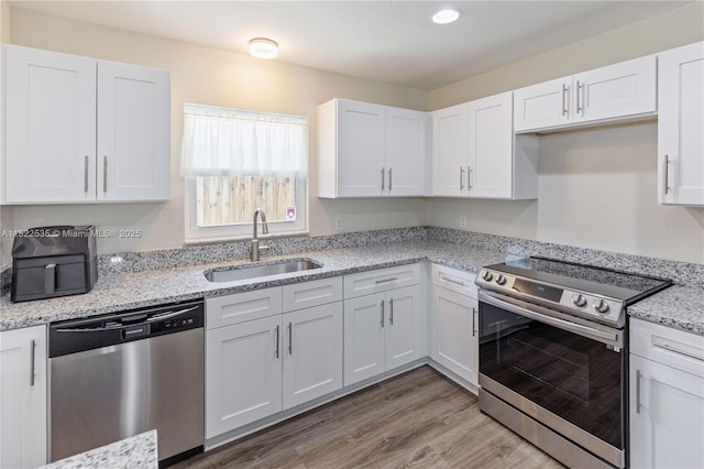 1712 Melvin Ave, Orlando, FL 32806 - kitchen with appliances with stainless steel finishes, white cabinetry, light wood-style flooring, and recessed lighting