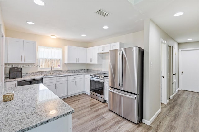 1712 Melvin Ave, Orlando, FL 32806 - kitchen featuring stainless steel appliances, light stone counters, white cabinets, light wood-style floors, and recessed lighting