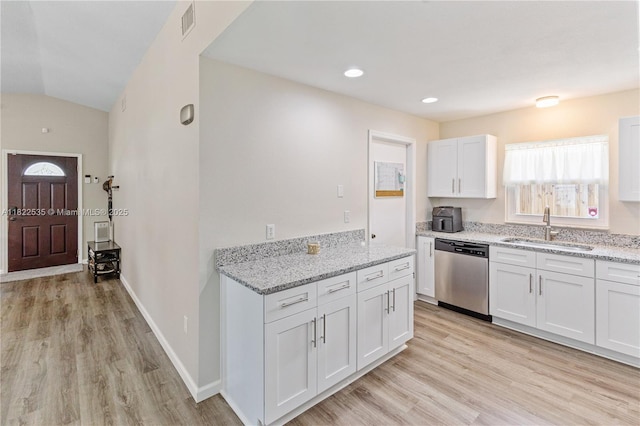 1712 Melvin Ave, Orlando, FL 32806 - kitchen featuring stainless steel dishwasher, light wood-type flooring, white cabinets, light stone counters, and lofted ceiling