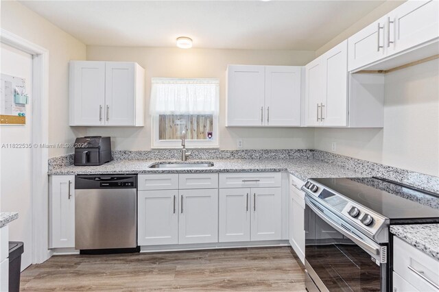 1712 Melvin Ave, Orlando, FL 32806 - kitchen featuring stainless steel appliances, white cabinets, light stone counters, and light wood-type flooring