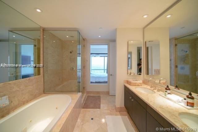 1425 Brickell Ave Unit 48C, Miami, FL 33131 - full bathroom featuring a whirlpool tub, a stall shower, double vanity, recessed lighting, and tile patterned floors