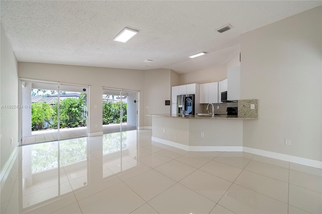 9408 SW 156th Pl, Miami, FL 33196 - kitchen with stainless steel fridge with ice dispenser, vaulted ceiling, white cabinetry, backsplash, and light stone countertops