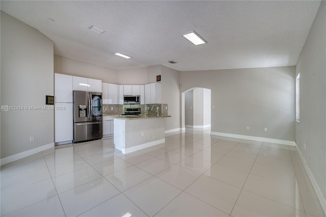 9408 SW 156th Pl, Miami, FL 33196 - kitchen with appliances with stainless steel finishes, arched walkways, decorative backsplash, white cabinets, and light stone counters