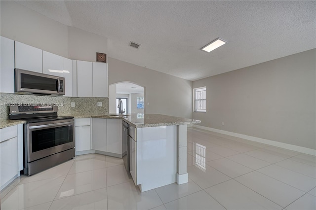 9408 SW 156th Pl, Miami, FL 33196 - kitchen with appliances with stainless steel finishes, backsplash, arched walkways, a peninsula, and a textured ceiling