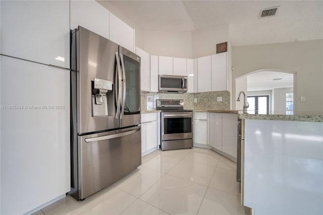 9408 SW 156th Pl, Miami, FL 33196 - kitchen with appliances with stainless steel finishes, arched walkways, decorative backsplash, light stone counters, and white cabinetry
