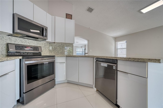 9408 SW 156th Pl, Miami, FL 33196 - kitchen with stainless steel appliances, white cabinets, arched walkways, tasteful backsplash, and a textured ceiling
