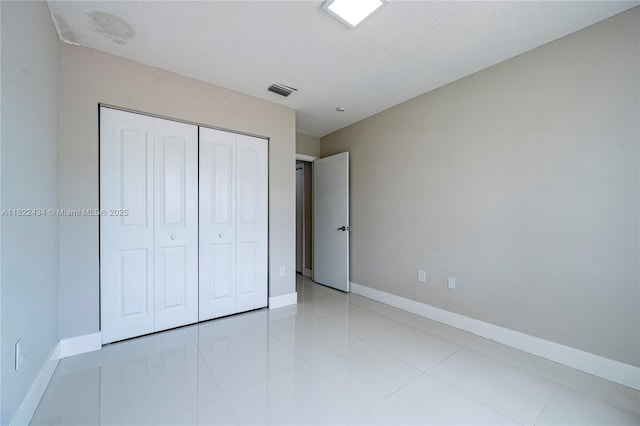 9408 SW 156th Pl, Miami, FL 33196 - unfurnished bedroom with a textured ceiling, a closet, and light tile patterned flooring