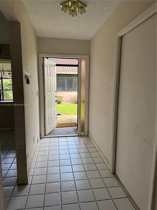 3313 W Inverrary Blvd W, Lauderhill, FL 33319 - doorway to outside featuring a textured wall, a textured ceiling, light tile patterned floors, and a chandelier