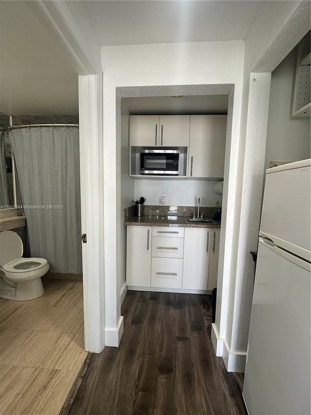 700 Biltmore Way Unit 1216, Coral Gables, FL 33134 - kitchen featuring freestanding refrigerator, stainless steel microwave, dark wood-style floors, and white cabinetry