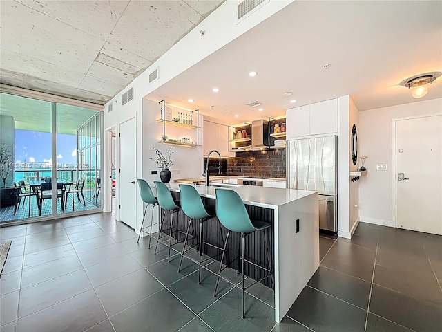 3301 NE 1st Ave Unit H1215, Miami, FL 33137 - kitchen with built in fridge, open shelves, tasteful backsplash, wall chimney exhaust hood, and a breakfast bar
