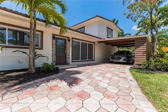 rear view of property with stucco siding, a tiled roof, and a carport