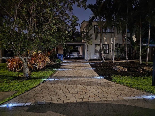 view of front of home featuring decorative driveway, an attached carport, and stucco siding