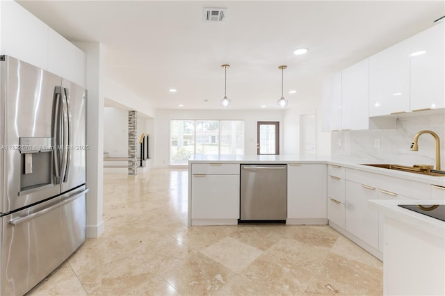 kitchen featuring appliances with stainless steel finishes, white cabinetry, a peninsula, decorative backsplash, and modern cabinets