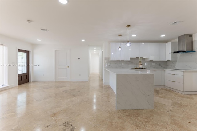 kitchen with wall chimney exhaust hood, modern cabinets, white cabinets, decorative backsplash, and recessed lighting