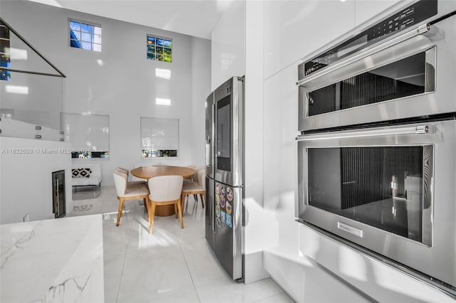 942 Lavender Cir, Weston, FL 33327 - kitchen featuring appliances with stainless steel finishes, light stone countertops, white cabinets, modern cabinets, and a towering ceiling