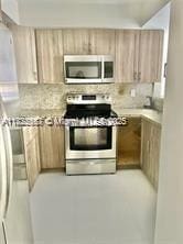 17570 Atlantic Blvd Unit 119, Sunny Isles Beach, FL 33160 - kitchen featuring stainless steel appliances, light brown cabinetry, backsplash, and light countertops