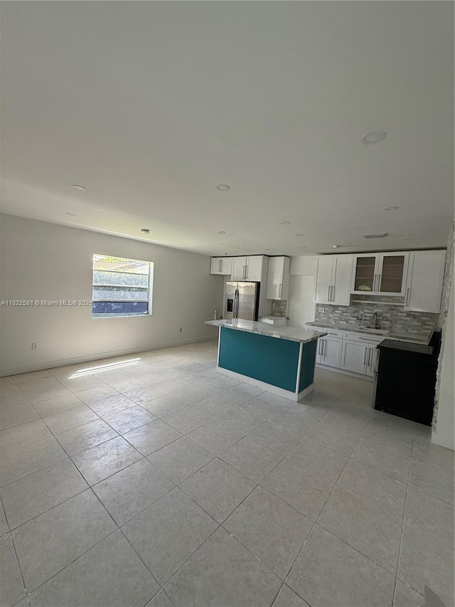 9801 SW 56th St, Miami, FL 33165 - kitchen featuring stainless steel fridge, light tile patterned flooring, white cabinets, a center island, and decorative backsplash