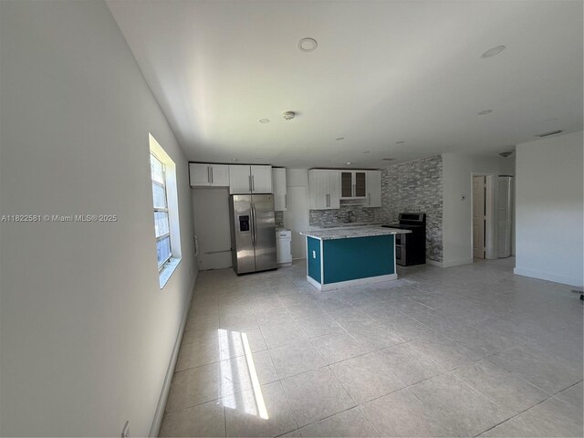 9801 SW 56th St, Miami, FL 33165 - kitchen with stainless steel fridge, decorative backsplash, a kitchen island, white cabinetry, and light tile patterned flooring