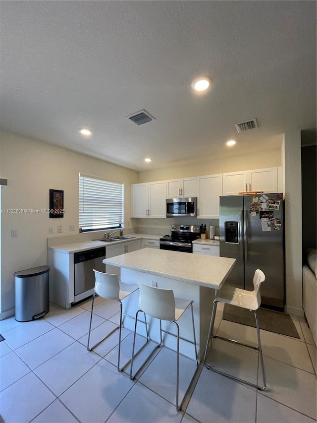 10586 W 33rd Ct Unit 10586, Hialeah, FL 33018 - kitchen with appliances with stainless steel finishes, a center island, white cabinets, light countertops, and a kitchen bar