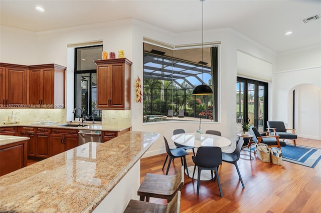 2489 Eagle Watch Ln, Weston, FL 33327 - kitchen featuring dishwasher, wood finished floors, arched walkways, light stone counters, and crown molding