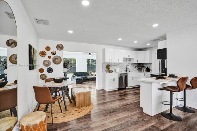 1772 SW 43rd Ave, Fort Lauderdale, FL 33317 - kitchen with dishwasher, light countertops, dark wood-style flooring, white cabinetry, and a breakfast bar area