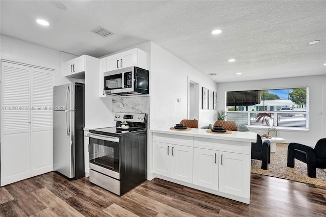 1772 SW 43rd Ave, Fort Lauderdale, FL 33317 - kitchen with stainless steel appliances, a peninsula, dark wood finished floors, a textured ceiling, and white cabinets