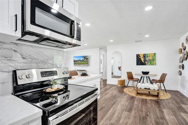 1772 SW 43rd Ave, Fort Lauderdale, FL 33317 - kitchen featuring appliances with stainless steel finishes, white cabinets, a textured ceiling, arched walkways, and recessed lighting