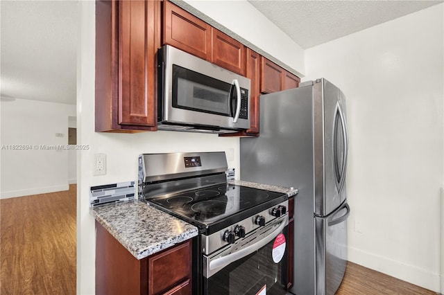 1150 N Liberty Ave Unit 1150G, Homestead, FL 33034 - kitchen featuring stainless steel appliances, light wood-type flooring, a textured ceiling, and light stone counters