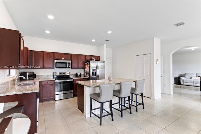 3557 W 94th Ter, Hialeah, FL 33018 - kitchen with stainless steel appliances, arched walkways, a kitchen bar, a center island, and light tile patterned floors