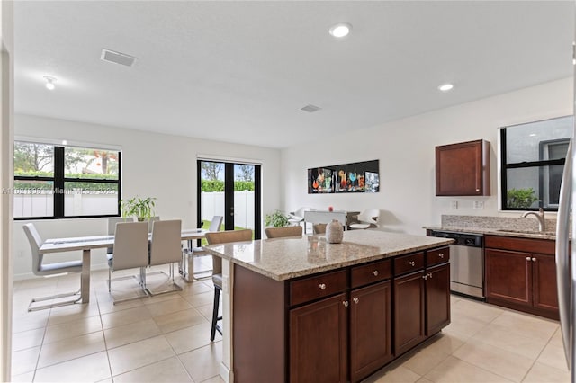 3557 W 94th Ter, Hialeah, FL 33018 - kitchen featuring dishwasher, french doors, a center island, light stone counters, and a kitchen breakfast bar