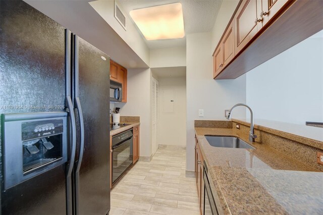 347 N New River Dr E Unit 1505, Fort Lauderdale, FL 33301 - kitchen with black appliances, light stone counters, and brown cabinets