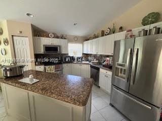 126 Chestnut Cir, Royal Palm Beach, FL 33411 - kitchen featuring stainless steel appliances, white cabinetry, dark stone counters, light tile patterned floors, and a center island