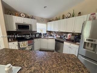 126 Chestnut Cir, Royal Palm Beach, FL 33411 - kitchen with stainless steel appliances, white cabinets, lofted ceiling, and dark stone countertops