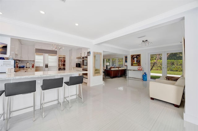 11230 SW 69th Ct, Pinecrest, FL 33156 - kitchen featuring appliances with stainless steel finishes, french doors, ornamental molding, open floor plan, and a kitchen bar