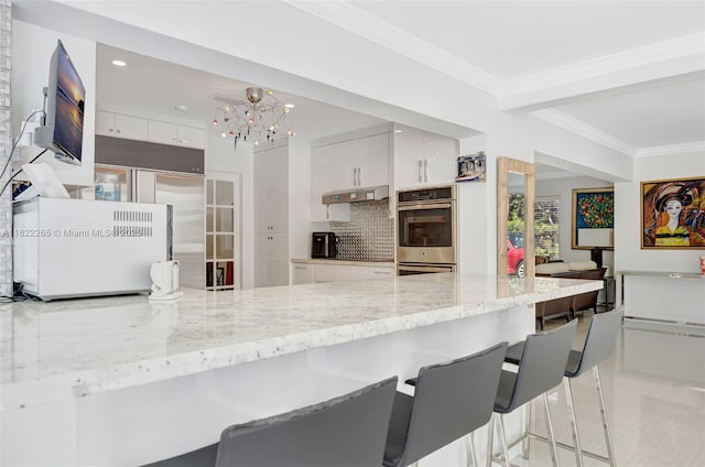 11230 SW 69th Ct, Pinecrest, FL 33156 - kitchen featuring stainless steel appliances, white cabinets, a breakfast bar, modern cabinets, and crown molding