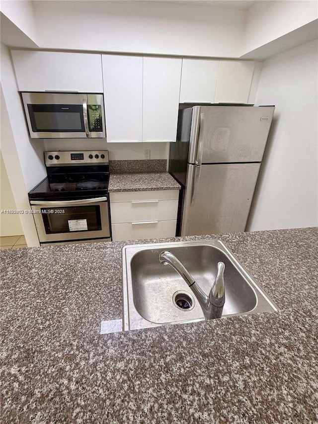 10001 W Atlantic Blvd Unit 321, Coral Springs, FL 33071 - kitchen featuring stainless steel appliances, white cabinets, and dark stone counters