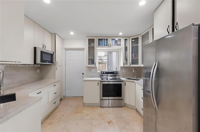 1601 Bay Rd Unit 4, Miami Beach, FL 33139 - kitchen with appliances with stainless steel finishes, backsplash, recessed lighting, white cabinets, and glass insert cabinets
