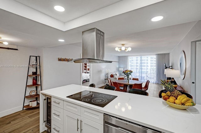 600 Three Islands Blvd Unit 615, Hallandale Beach, FL 33009 - kitchen with black electric stovetop, light wood-style floors, open floor plan, island exhaust hood, and white cabinetry