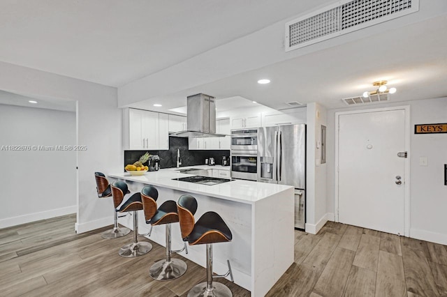 600 Three Islands Blvd Unit 615, Hallandale Beach, FL 33009 - kitchen with island exhaust hood, appliances with stainless steel finishes, a peninsula, a breakfast bar, and light countertops