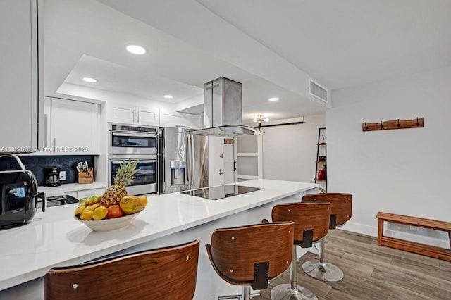 600 Three Islands Blvd Unit 615, Hallandale Beach, FL 33009 - kitchen with island exhaust hood, a peninsula, appliances with stainless steel finishes, light countertops, and a breakfast bar area