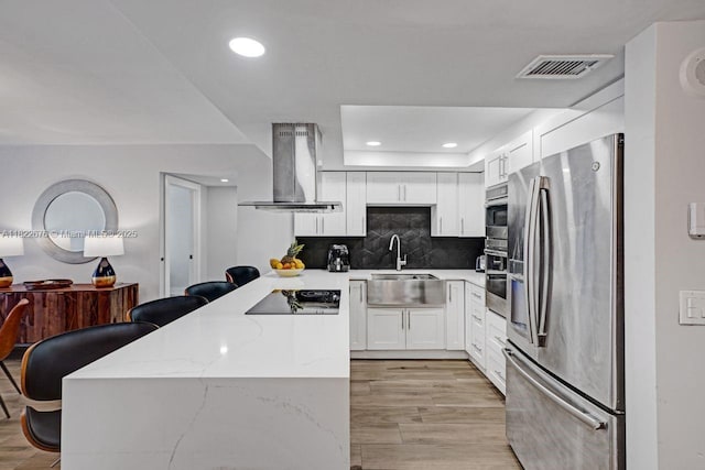 600 Three Islands Blvd Unit 615, Hallandale Beach, FL 33009 - kitchen with stainless steel appliances, range hood, a peninsula, white cabinets, and light wood-style floors