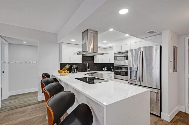 600 Three Islands Blvd Unit 615, Hallandale Beach, FL 33009 - kitchen with appliances with stainless steel finishes, island exhaust hood, a peninsula, decorative backsplash, and white cabinetry