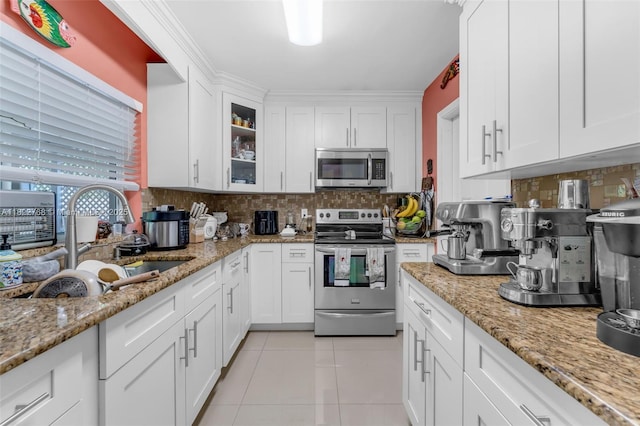 28540 SW 146th Ave, Homestead, FL 33033 - kitchen with appliances with stainless steel finishes, white cabinets, light tile patterned floors, glass insert cabinets, and tasteful backsplash
